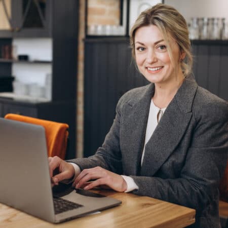 Frau sitzt vor Laptop, ist erfolgreich, weil sie sich hat eine Website erstellen lassen